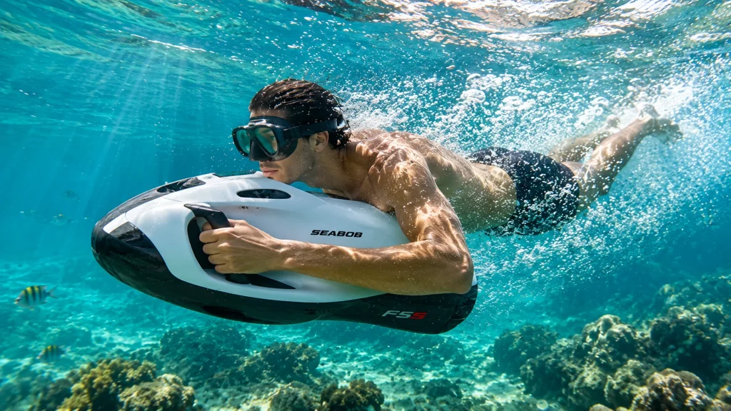 Snorkeler using a white SEABOB F5 S underwater scooter above a coral reef in clear turquoise water.