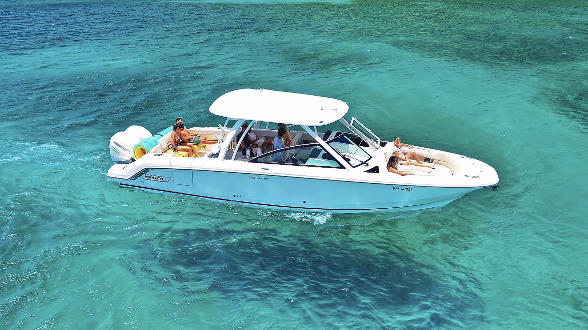 SEABREEZE Boston Whaler 320 Vantage cruising through turquoise water with guests relaxing on the bow and aft seating