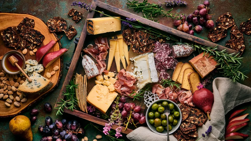 Gourmet cheese and charcuterie board with artisan cheeses, cured meats, grapes, olives, pears, nuts and crackers.